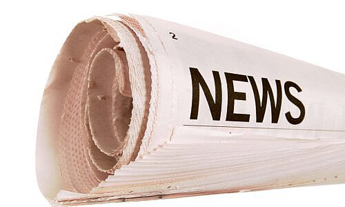 Rolled up newspaper with news headline set against a white background
